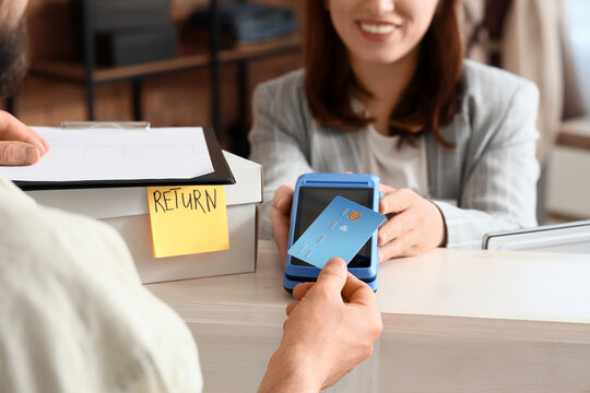 Customer returning purchase with credit card payment at retail store counter, transaction processing and refund, a sales associate handles the transaction with a payment terminal