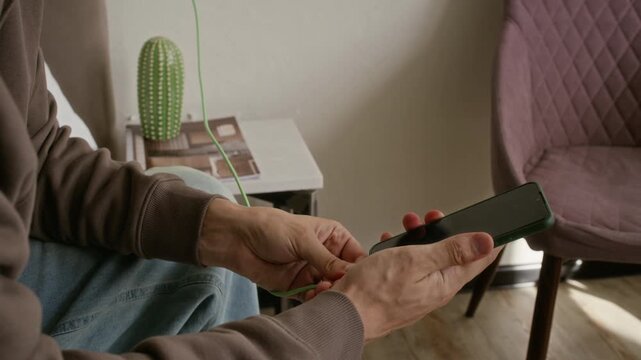 Handheld shot of Caucasian young man plugging charger into wall outlet and connecting cable to smartphone in hotel room. Footage is ideal for travel technology and mobile connectivity commercials