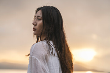 Fototapeta premium 夕暮れの海にいる女性