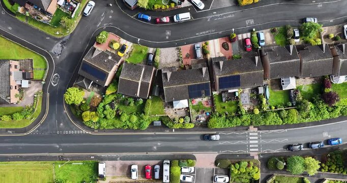 Directly overhead aerial view of a residential neighbourhood in Penrith Cumbria England showing family homes private gardens parked vehicles road markings pedestrian crossing and suburban street