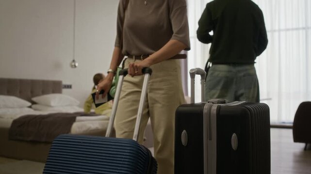 Stab shot of Caucasian family entering hotel room with suitcases, child running ahead while parents walk towards window. Footage ideal for travel, tourism, and family vacation marketing campaigns