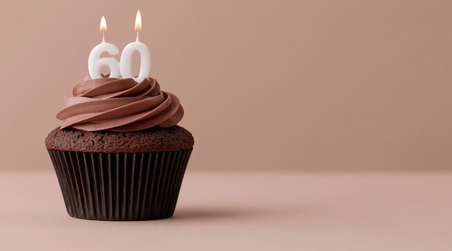 Chocolate cupcake with number 60 lit candles on beige background