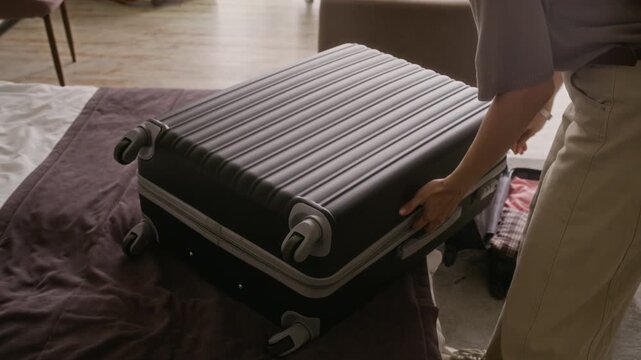 Cropped shot of young woman unzipping and opening suitcase while unpacking. Video is perfect for travel booking platforms, vacation planning advertisements and hospitality marketing campaigns