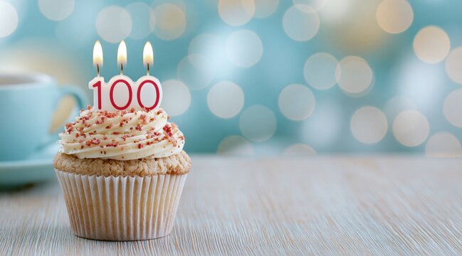 Cupcake with number 100 candles on wooden table with bokeh background