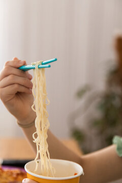long strands of noodles dangling from chopsticks