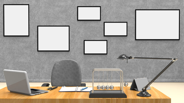 Scrivania ordinata con laptop, taccuino e pendolo di Newton davanti a parete con cornici vuote. Immagine ideale per produttivit&agrave;, business, smart working e concetti aziendali.