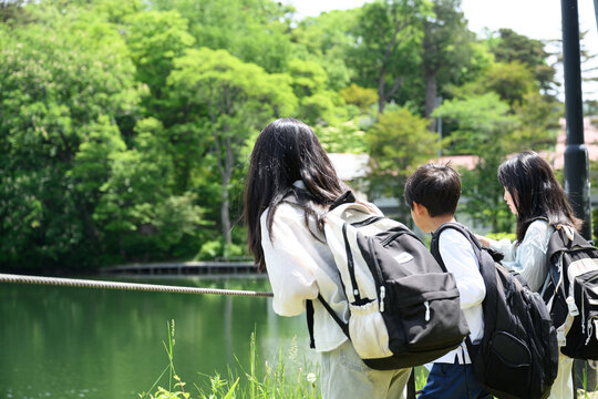 新緑の湖畔で地図を見ながら野外学習やオリエンテーリングをする小学生グループ