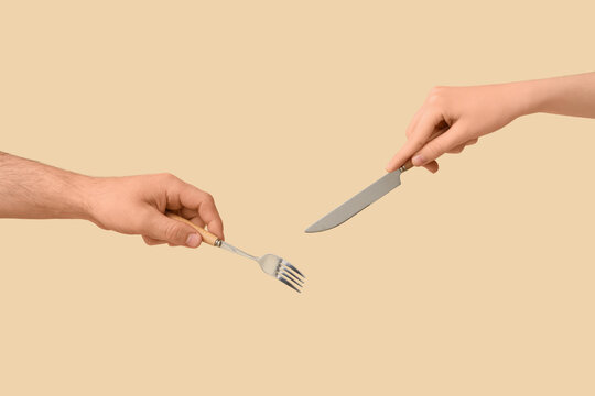 Two hands holding fork and knife for eating, meal preparation, and dining experience on neutral background