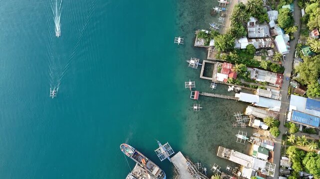 Aerial drone view of Liminangcong Port, revealing stilt houses and coastal housing along a tropical seascape, Philippines