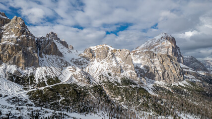 Obraz premium Aerial View of Falzarego Pass with Snowy Peaks and Winding Road, Dolomites, Italy