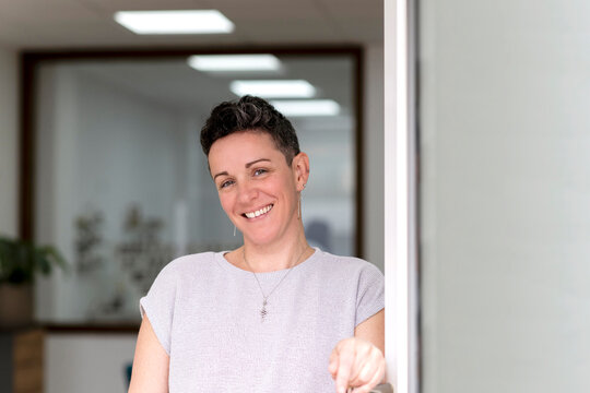 Smiling woman with short hair standing in office doorway