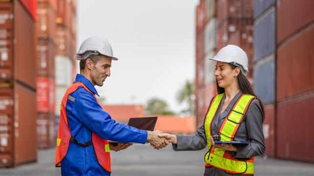 Two workers shaking hands at shipping port, Logistics managers shaking hands at container terminal after successful deal, Professional logistics team closing agreement in shipping port environment