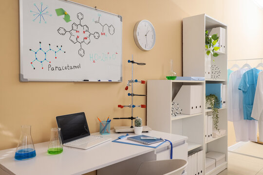 Modern chemistry laboratory workspace with paracetamol formula on whiteboard, scientific equipment, and laptop for research and education