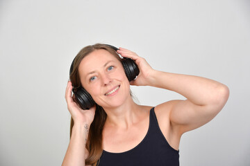 Naklejka premium Lächelnde Frau mit Kopfhörern genießt Musik und Audioinhalte. Modernes Lifestyle-Motiv für Streaming, Podcasts, Hörbücher, Entspannung, Freizeit und digitalen Medienkonsum. Echtfoto.