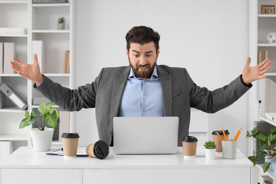 Frustrated businessman reacting to computer problem in office, stressful work situation, technology failure, business challenges