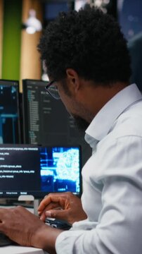 Vertical aspect footage of tech startup IT professional developing AI algorithms in high rise office during late night shift. man debugging neural network brain models on screens.