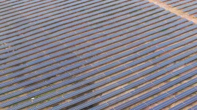 Cinematic drone shot moving forward above endless solar panels at a utility-scale solar farm, showcasing renewable energy infrastructure and sustainable electricity generation. 