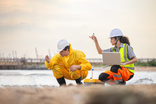 Team of environmental engineers collecting analyzing water quality samples at coastal industrial site, Professional scientists performing environmental monitoring and water pollution testing outdoors