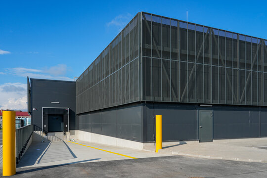 Modern logistics warehouse loading dock with mesh facade and service access area exterior view