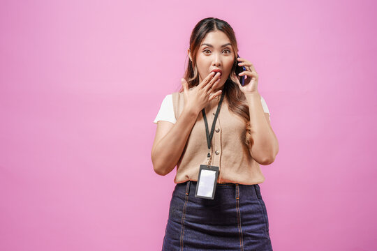 Shocked young Asian woman wearing her office attire is using smartphone to have a call.