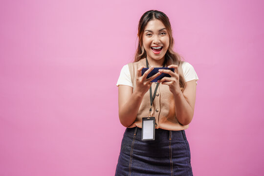 Joyful young Asian woman is watching streaming video or playing game on her smartphone.