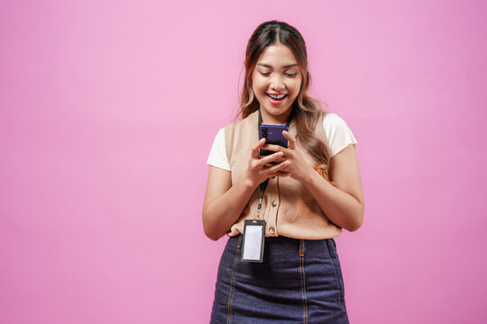 Cheerful young Asian woman is smiling while using smartphone to text someone or open social media.