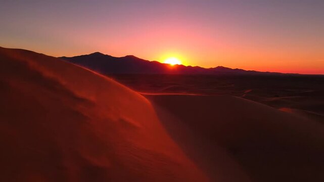 Golden sunset over windblown sand dunes in vast desert