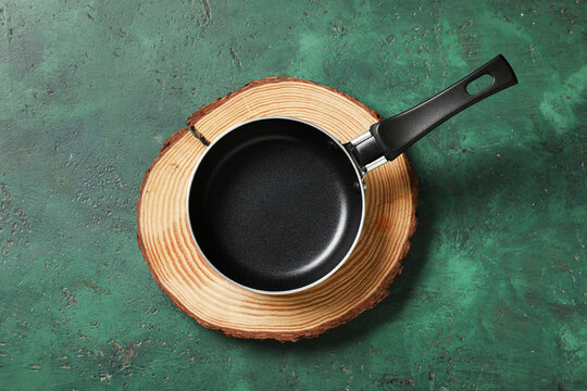 Empty black frying pan on natural wood slice, kitchen utensil for cooking and food preparation, top view