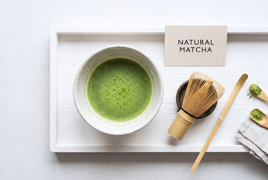 organic matcha tea ceremony setup with ceramic bowl and bamboo whisk on white wooden tray