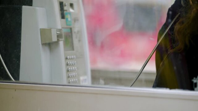 Woman Using Coin-Operated Public Telephone Housed In Glass Booths. - static shot