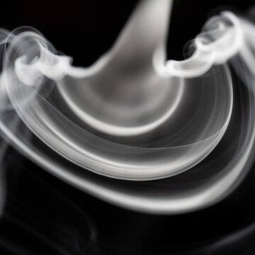 Smoke swirls create unique patterns on a dark surface in a quiet setting