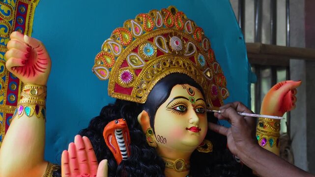 Artist painting hindu goddess idol face with festive devotion