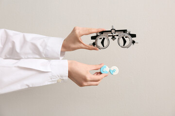 Doctor hands with optical trial frame and container of contact lenses on white background © Pixel-Shot