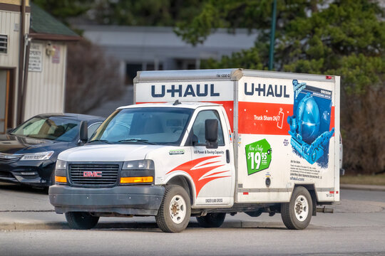 Calgary, Alberta, Canada. June 8, 2026. Three-quarter view of a white U-Haul moving truck parked on a city street next to a sidewalk curb.