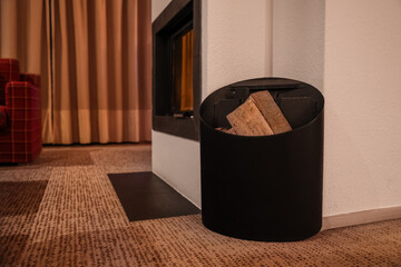 Obraz premium Modern fireplace with black log holder and firewood, cozy living room interior design, home heating and comfort