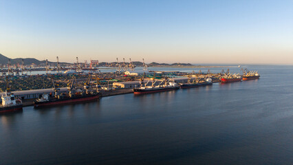 Obraz premium Commercial Port with Cargo Ships and Containers at Dusk