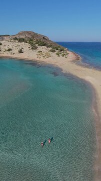 White sands meet turquoise waters at Simos Beach, Elafonisos Island Greece. Visitors enjoy sunbathing and swimming in this serene paradise, where vibrant nature creates an idyllic holiday escape.
