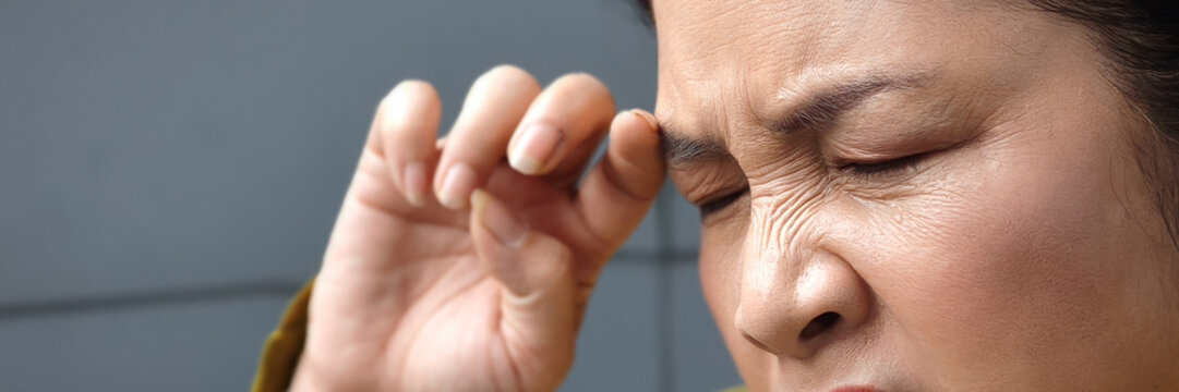 Asian middle aged woman suffering from irritated eye, concept image for optical health care, red eye allergy, eye care, allergic or itching or dry eye inflammation, closeup shot header crop