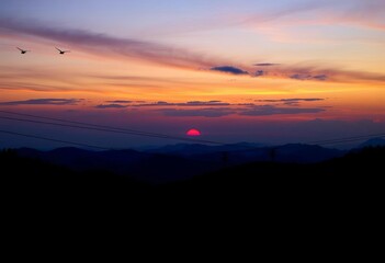 Obraz premium Set of diverse zipline silhouettes against sunset sky, cliff, sky