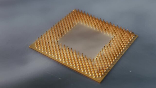 CPU processor with a pin grid array is revealed as white vapor dissipates. Macro shot shows golden pins on a dark reflective surface, representing advanced technology and intricate design