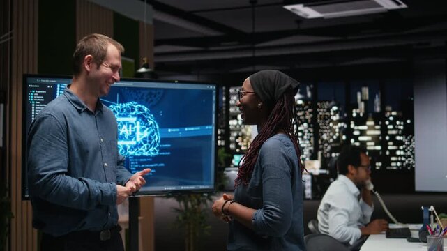 tech company IT staff members laughing in office, developing apps with AI. System administrators sharing jokes while waiting for AI to debug apps.