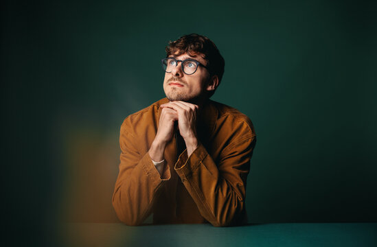 The man considers a business decision with glasses in a studio portrait