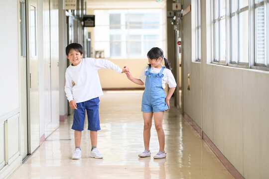 学校の廊下で手をつないで新入生を案内する上級生