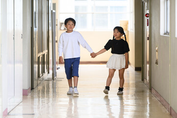 Fototapeta premium 学校の廊下で手をつないで新入生を案内する上級生