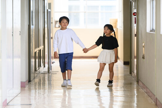 学校の廊下で手をつないで新入生を案内する上級生