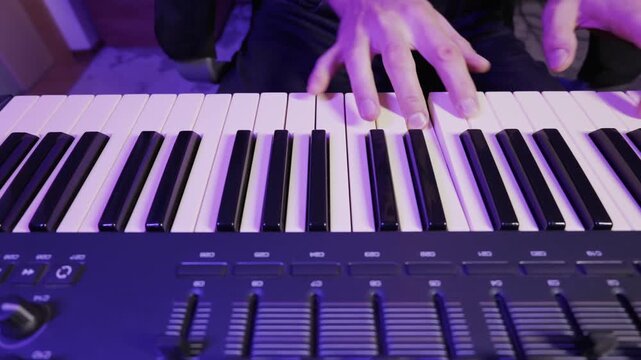 Male hands play chords and melodies on a digital piano keyboard. The scene is illuminated by a cool, atmospheric purple light, creating a modern and electronic mood.