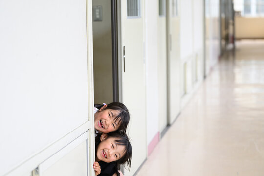 教室のドアからひょっこり顔を出す期待に満ちた新入生の女子小学生たち