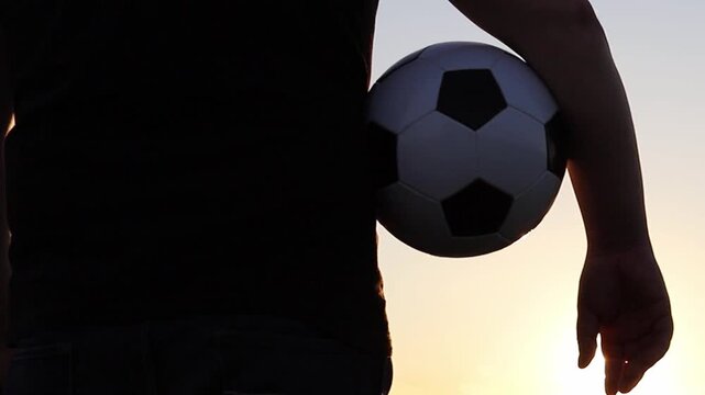 Player stands with a soccer ball under an orange sunset sky. This captures the passion for futbol and the excitement building for the 2026 World Cup across USA and Canada