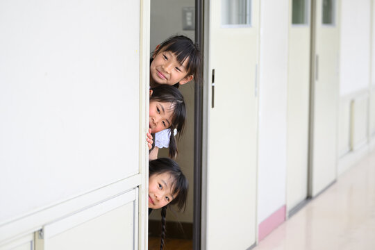 教室のドアからひょっこり顔を出す期待に満ちた新入生の女子小学生たち