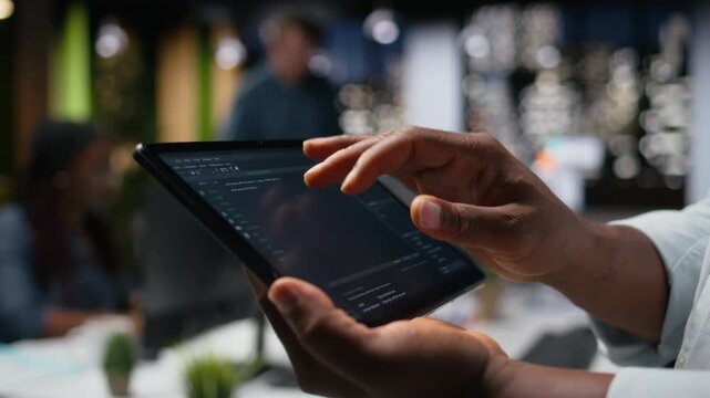 Close up of programmer typing code on touchscreen device, developing machine learning models to automate tasks in workspace with tablet workflow.